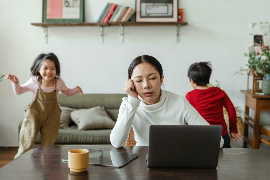 woman-working-on-laptop-while-kids-play-in-background